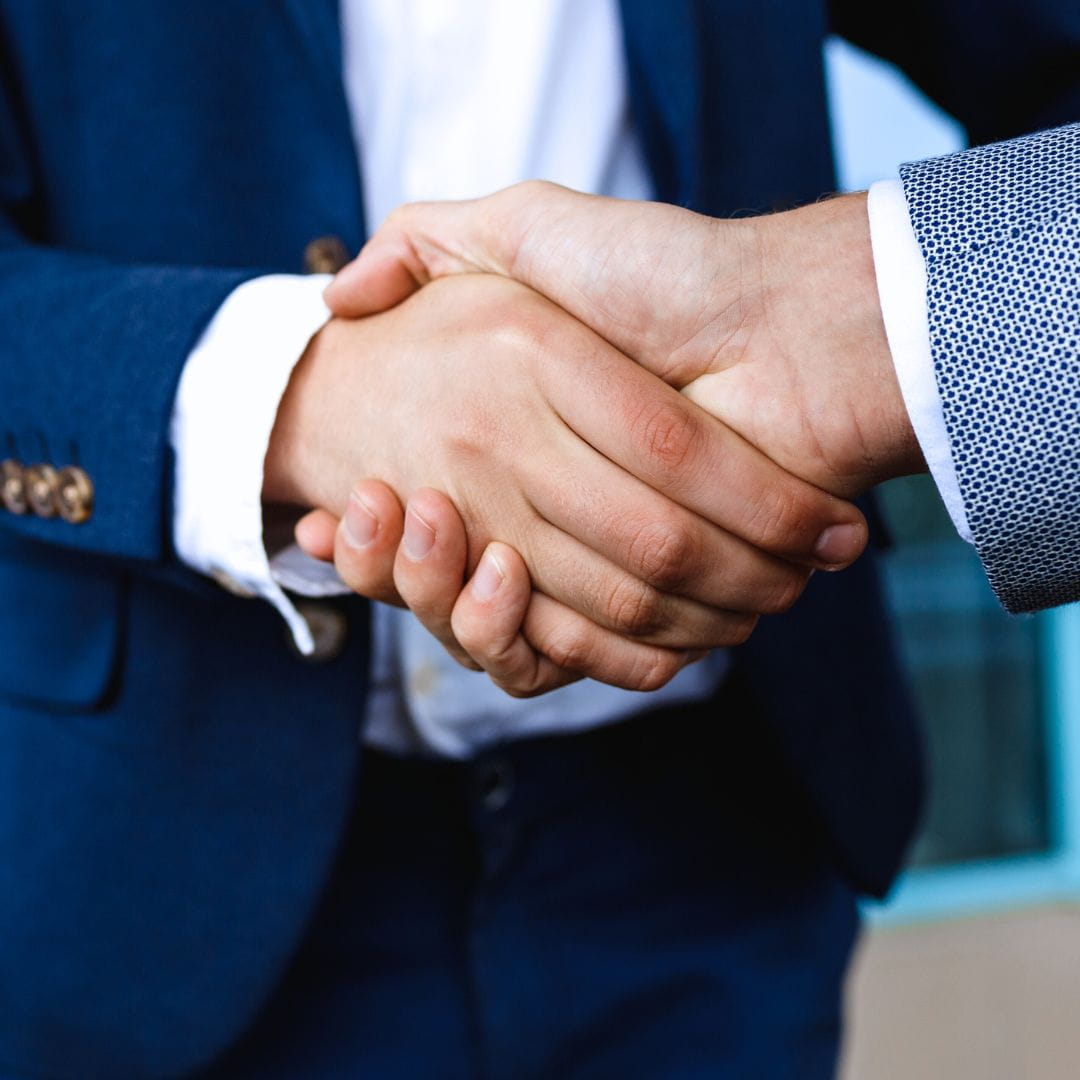 Close-up of two business professionals shaking hands to seal a broker partnership agreement.